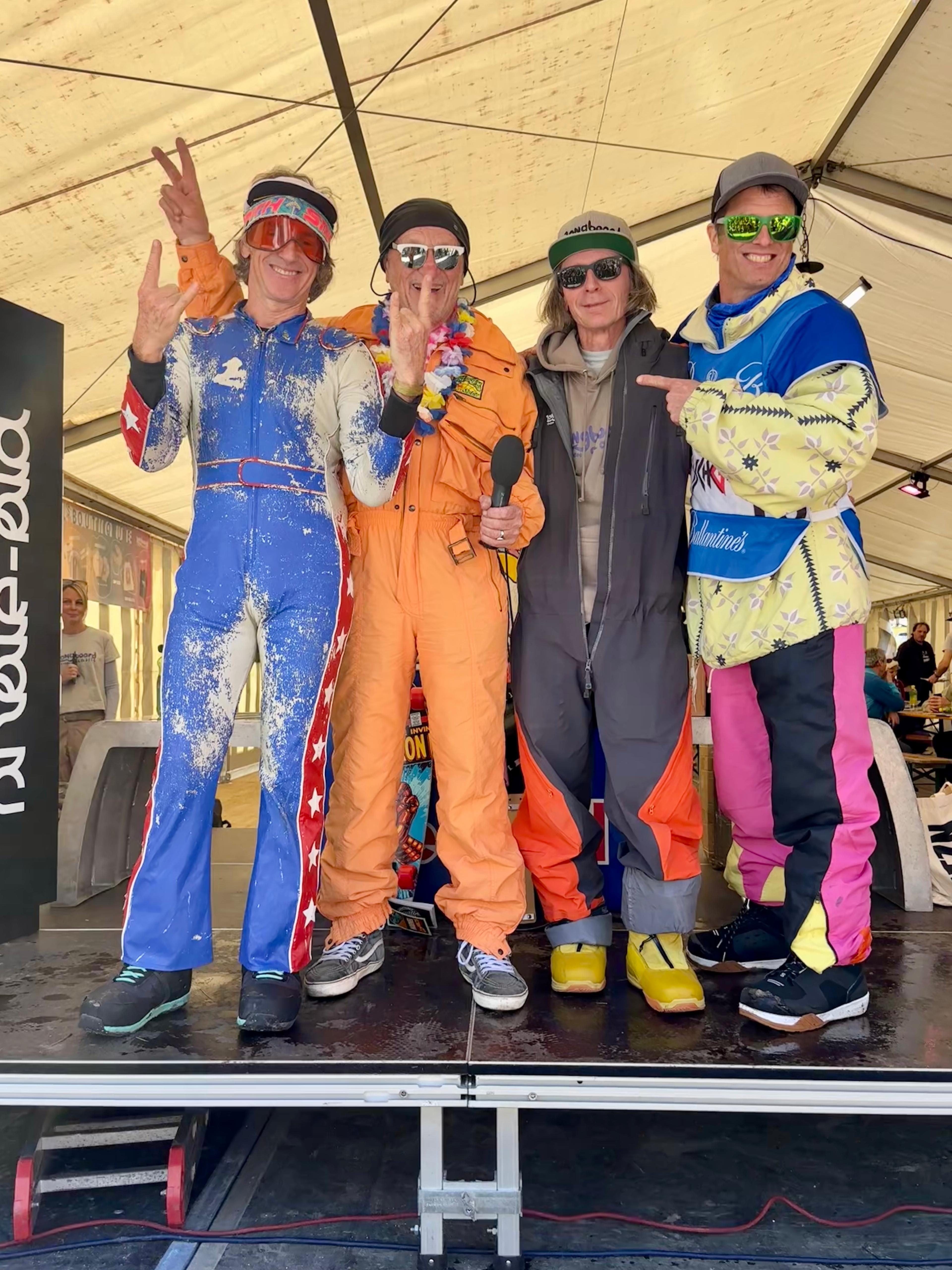 Vier Männer in bunten Retro-Outfits auf der Bühne, Peace-Zeichen