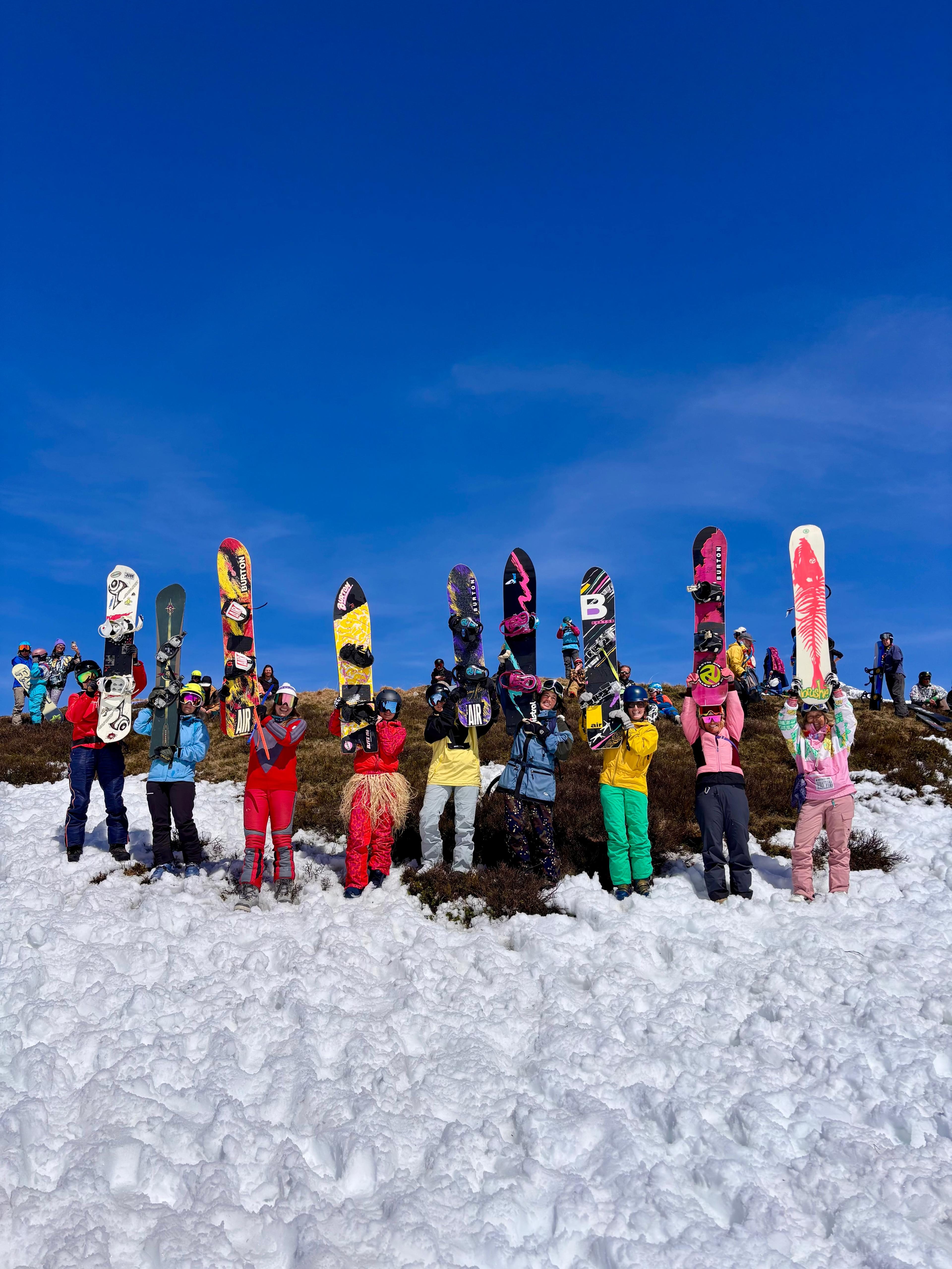 Kids halten ihre Snowboards in die Luft vor strahlendem blauen Himmel