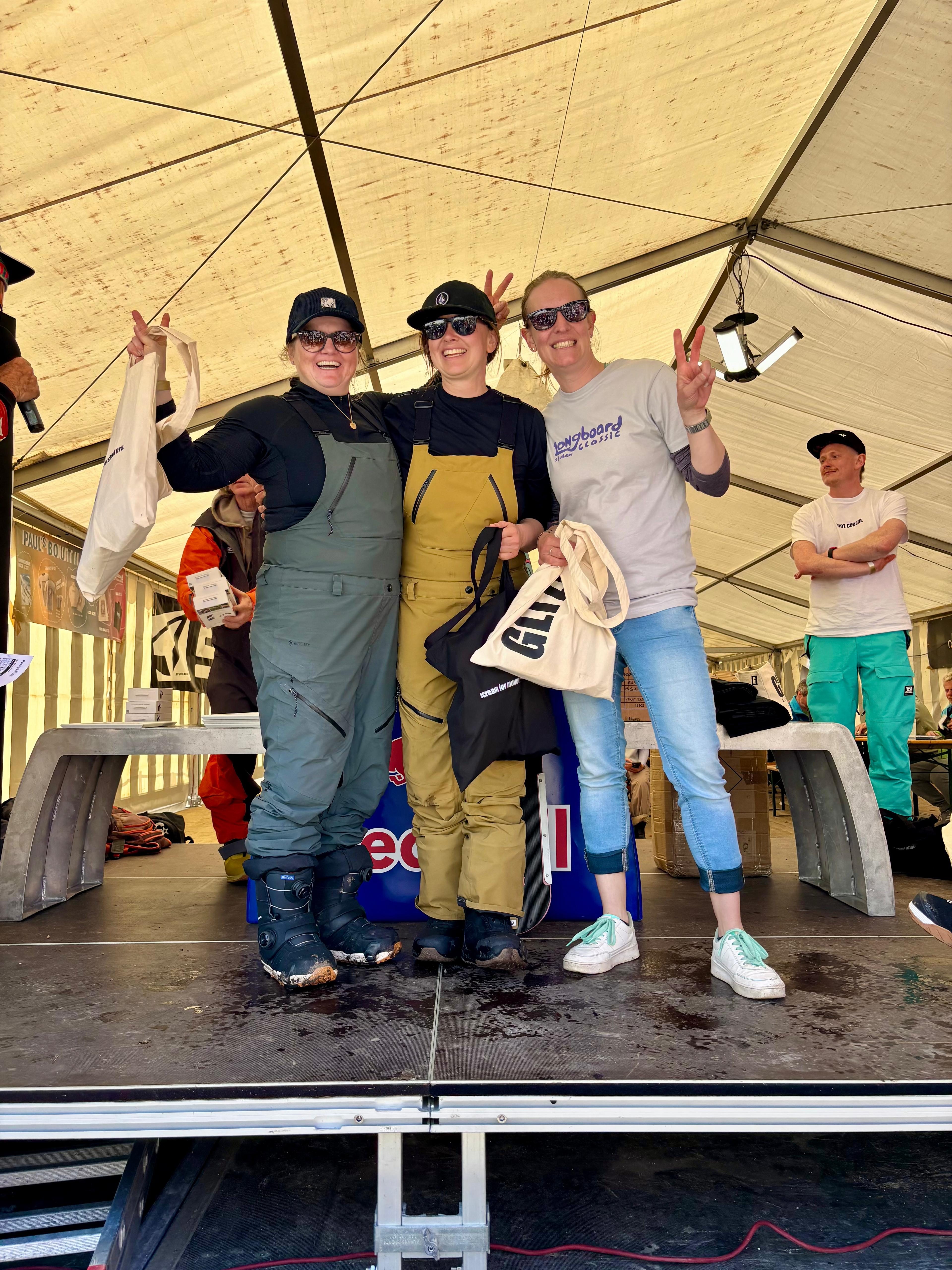 Siegerehrung – drei Damen auf der Bühne mit Urkunden und Goodboards Taschen
