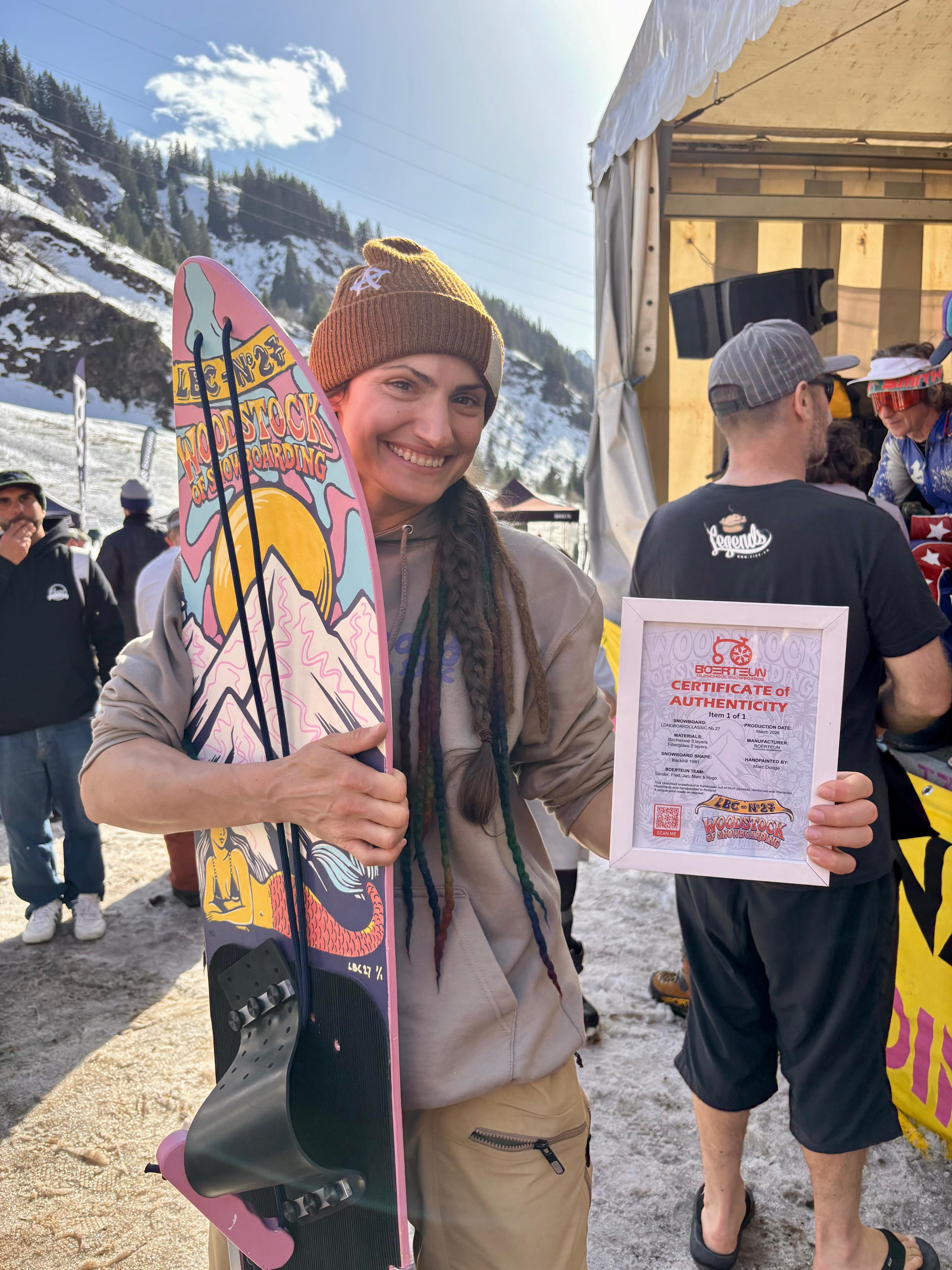 Frau mit Dreadlocks hält LBC Woodstock of Snowboarding Board und Certificate of Authenticity
